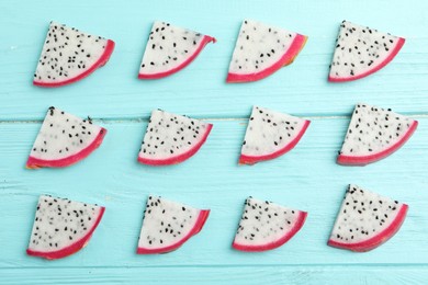 Slices of delicious dragon fruit (pitahaya) on light blue wooden table, flat lay