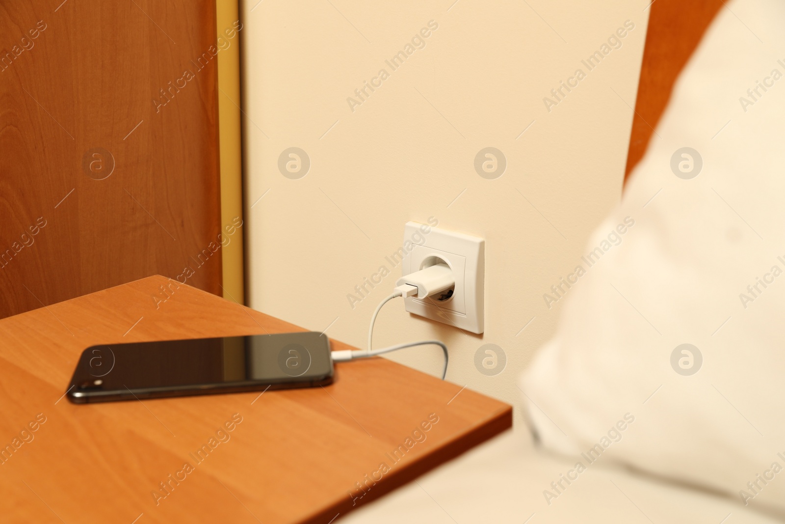 Photo of Modern smartphone charging from electric socket indoors