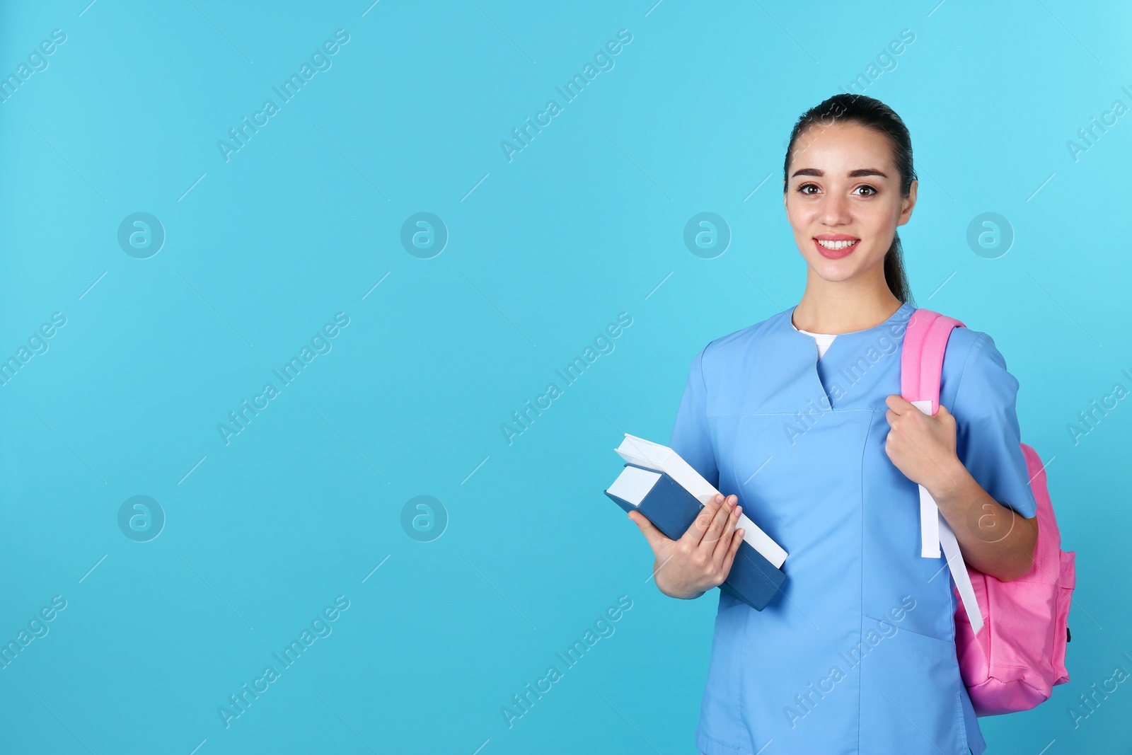 Photo of Young medical student with books and backpack on color background. Space for text