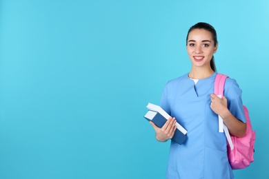 Young medical student with books and backpack on color background. Space for text