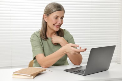 Photo of Happy woman having video chat via laptop at table indoors