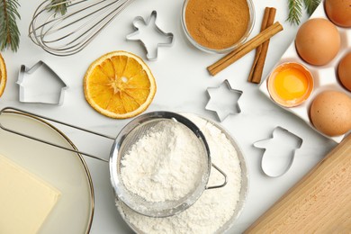 Photo of Flat lay composition with cookie cutters and ingredients on white table. Christmas biscuits