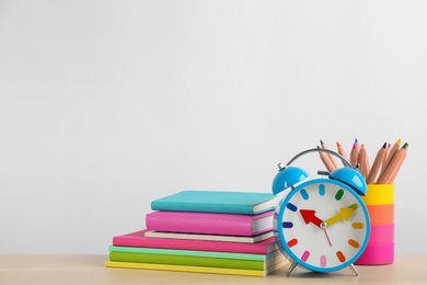 Photo of Different school stationery and alarm clock on table against white background, space for text. Back to school