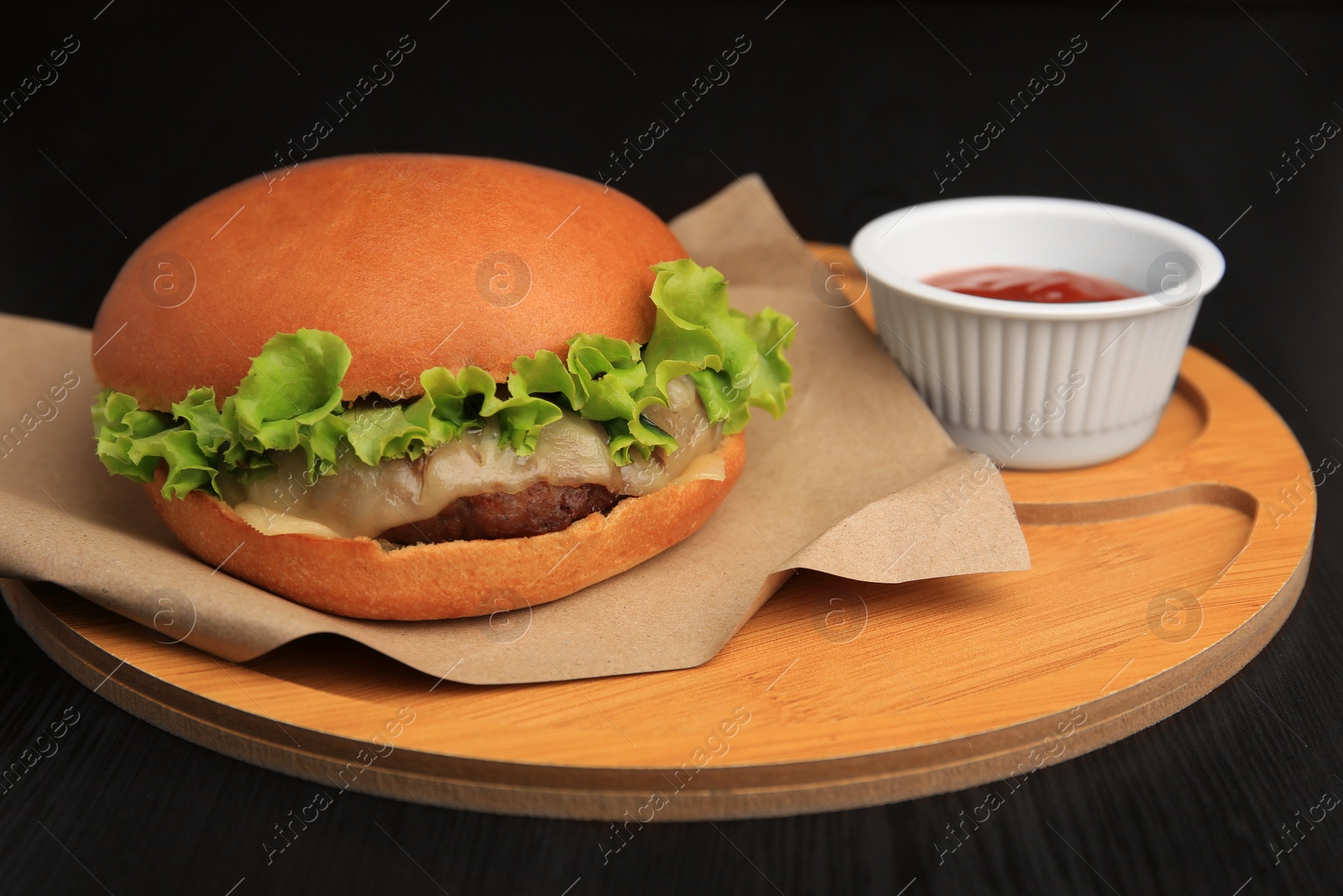 Photo of Board with tasty cheeseburger and sauce on wooden table, closeup