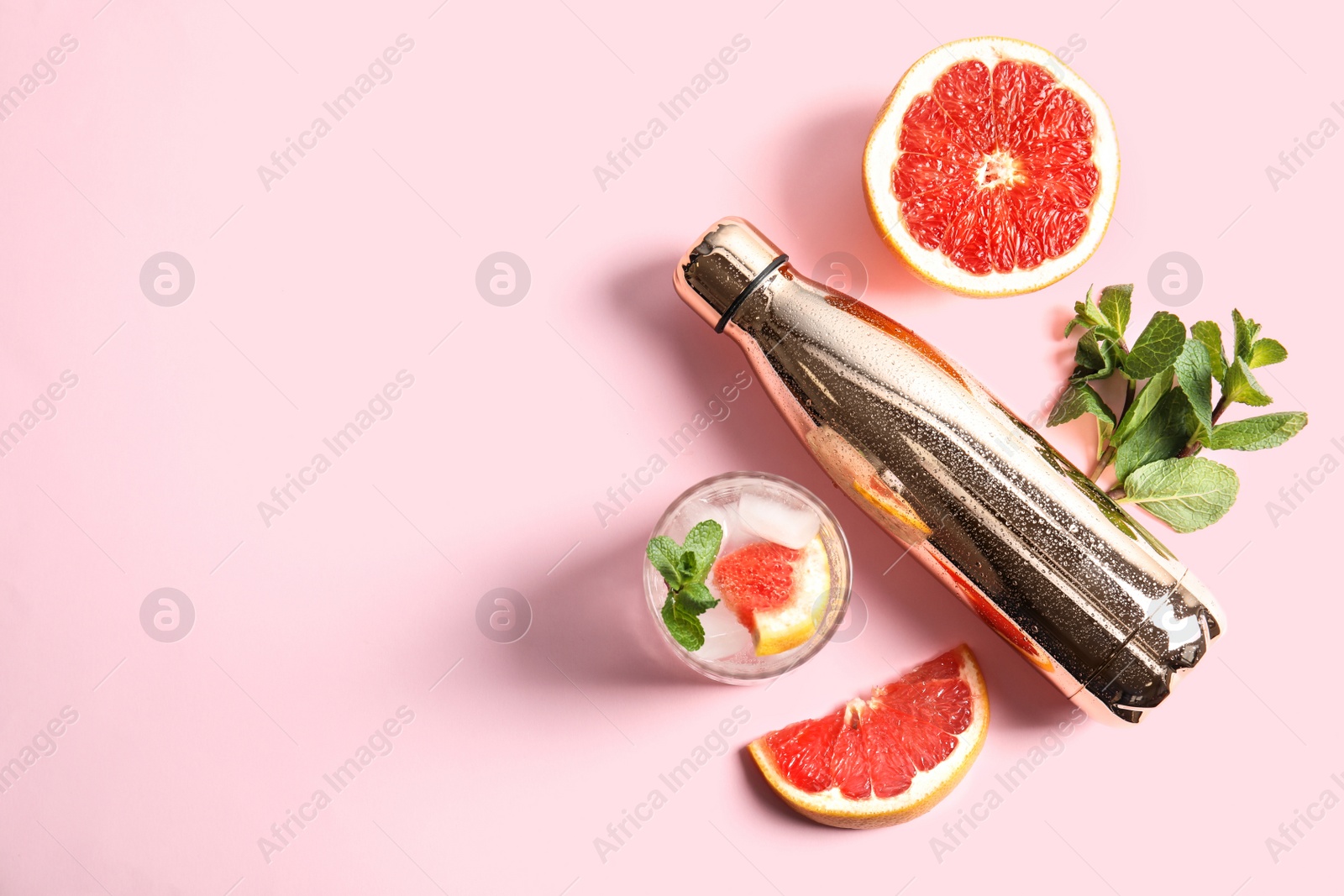 Photo of Flat lay composition with glass of infused water, grapefruits and bottle on color background. Space for text