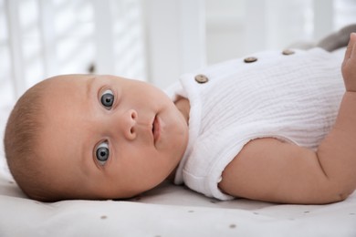 Photo of Cute little baby lying on bed at home, closeup