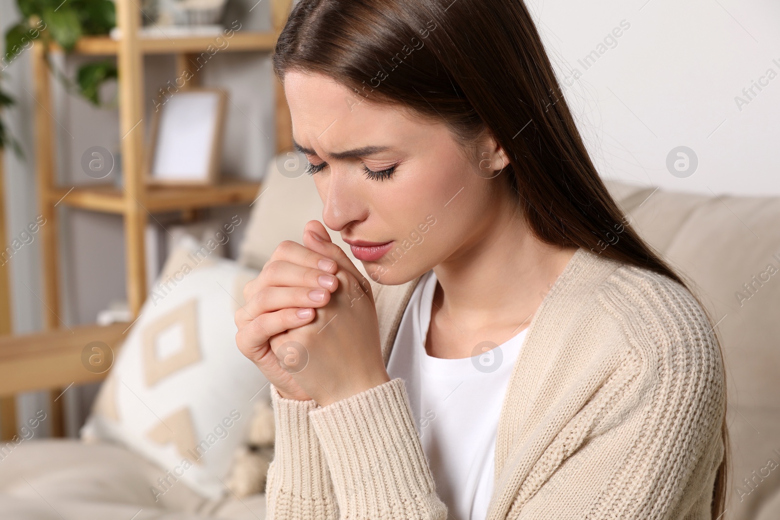 Photo of Woman with clasped hands praying at home