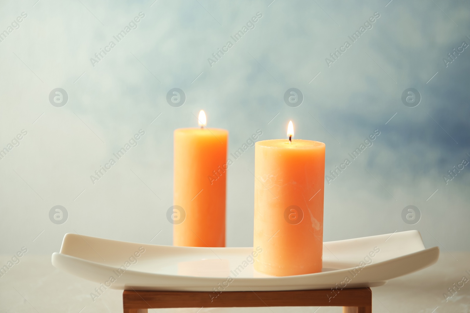 Photo of Decorative candles and stand against color background