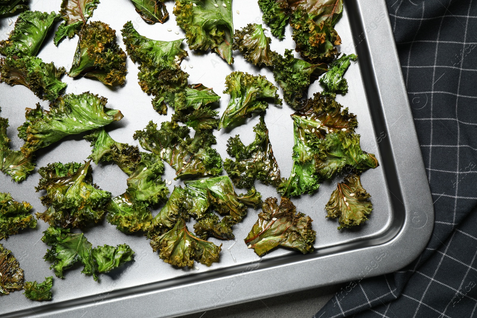 Photo of Tasty kale chips on baking sheet, top view