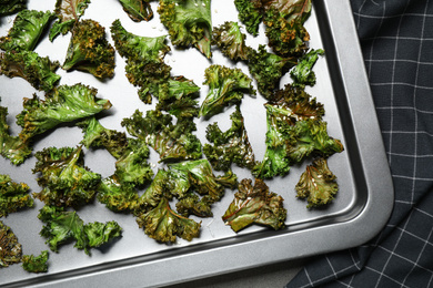 Photo of Tasty kale chips on baking sheet, top view