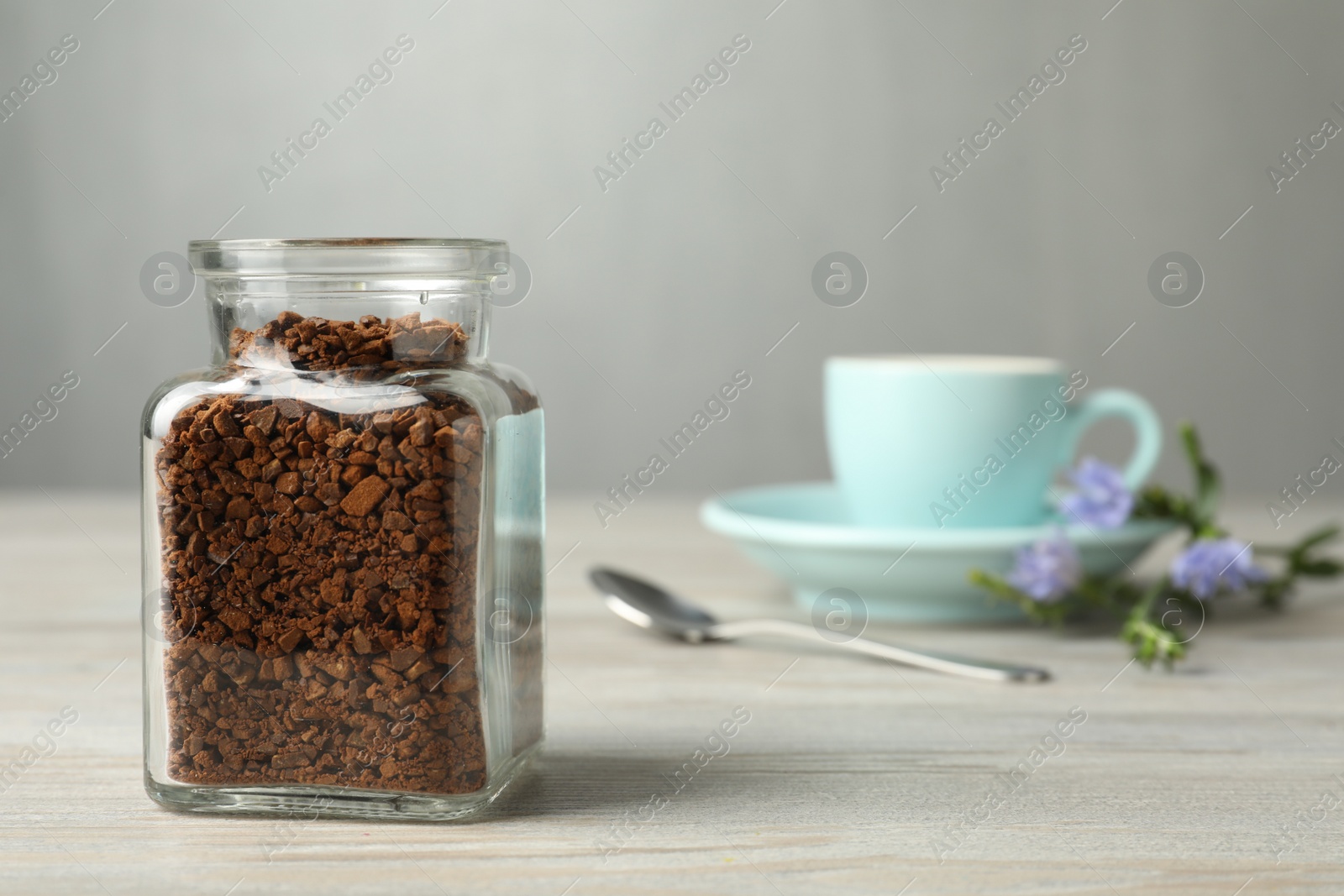 Photo of Jar of chicory granules on white wooden table, space for text