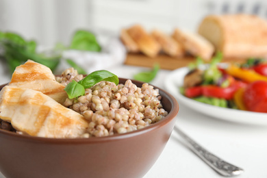 Photo of Bowl with tasty buckwheat porridge and meat, closeup