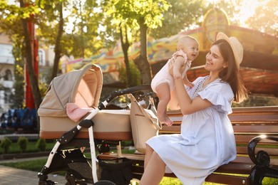 Happy mother with baby sitting on bench in park