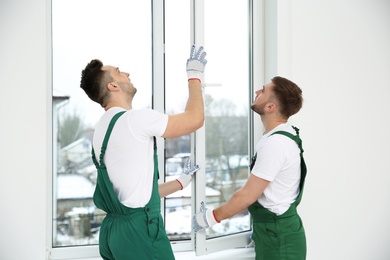 Photo of Construction workers installing plastic window in house