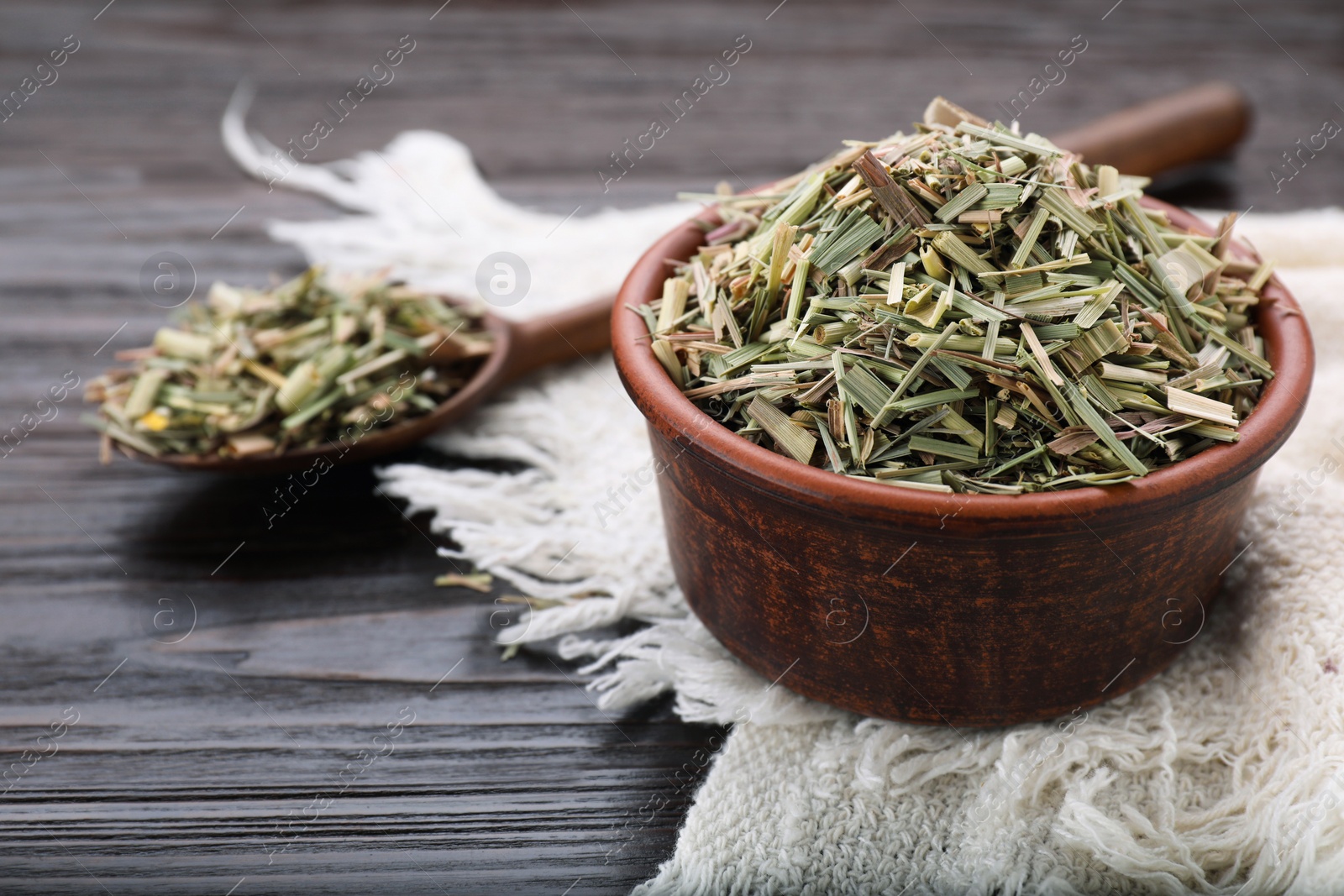 Photo of Bowl and spoon with aromatic dried lemongrass on wooden table. Space for text