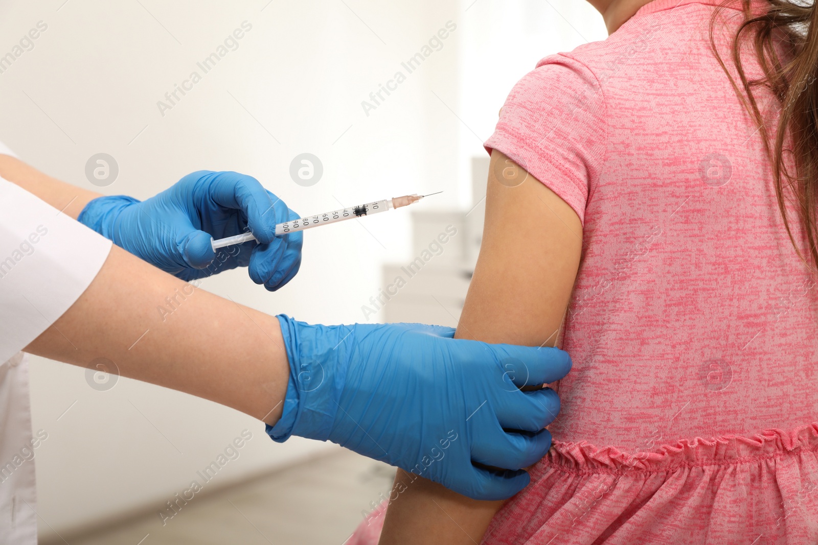 Photo of Doctor giving injection to little girl in hospital, closeup. Immunization concept