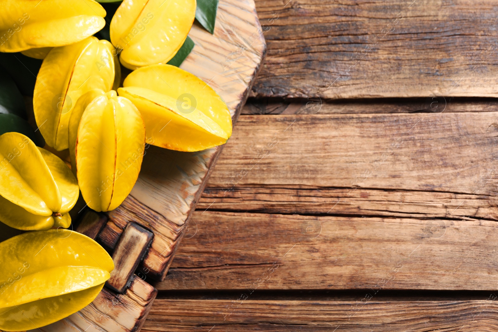 Photo of Delicious carambola fruits on wooden table, top view. Space for text