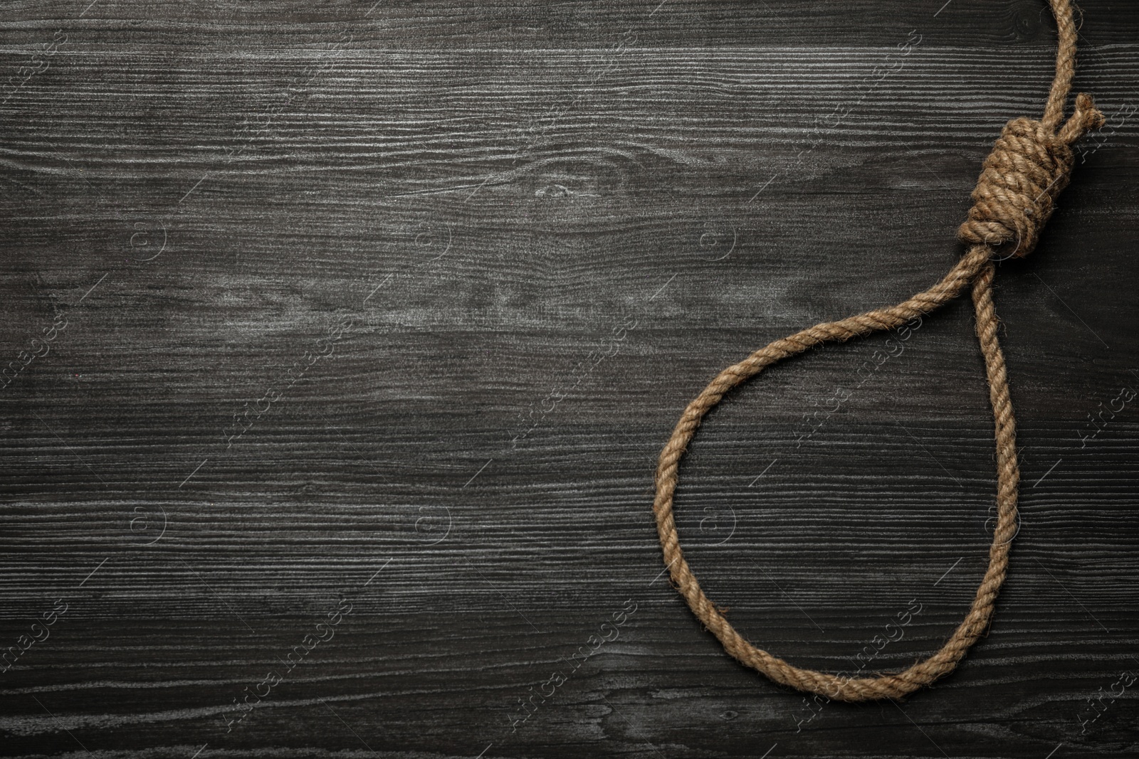 Photo of Rope noose on black wooden table, top view. Space for text