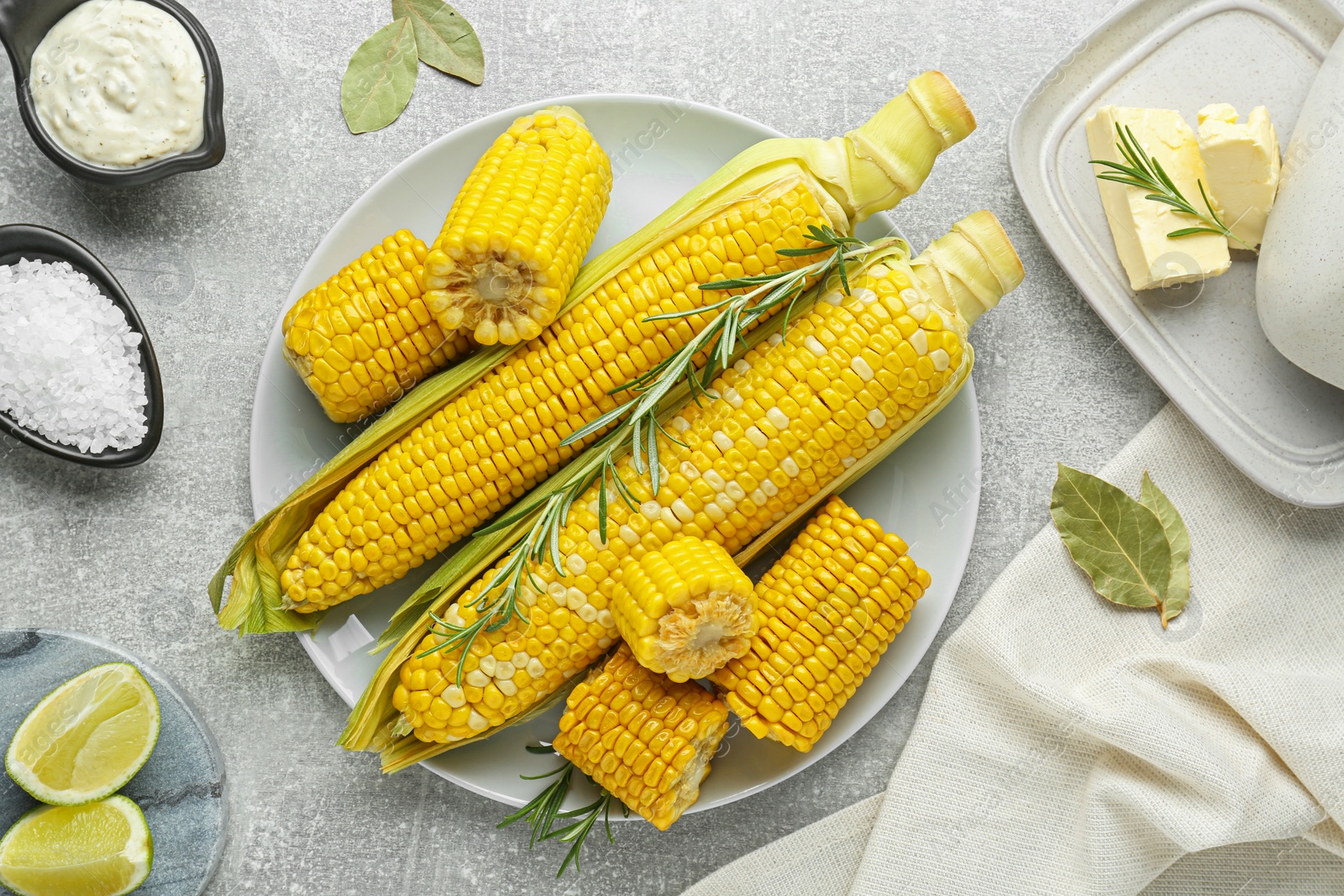 Photo of Flat lay composition with tasty boiled corn on light grey table