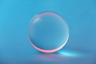 Photo of Transparent glass ball on light blue background