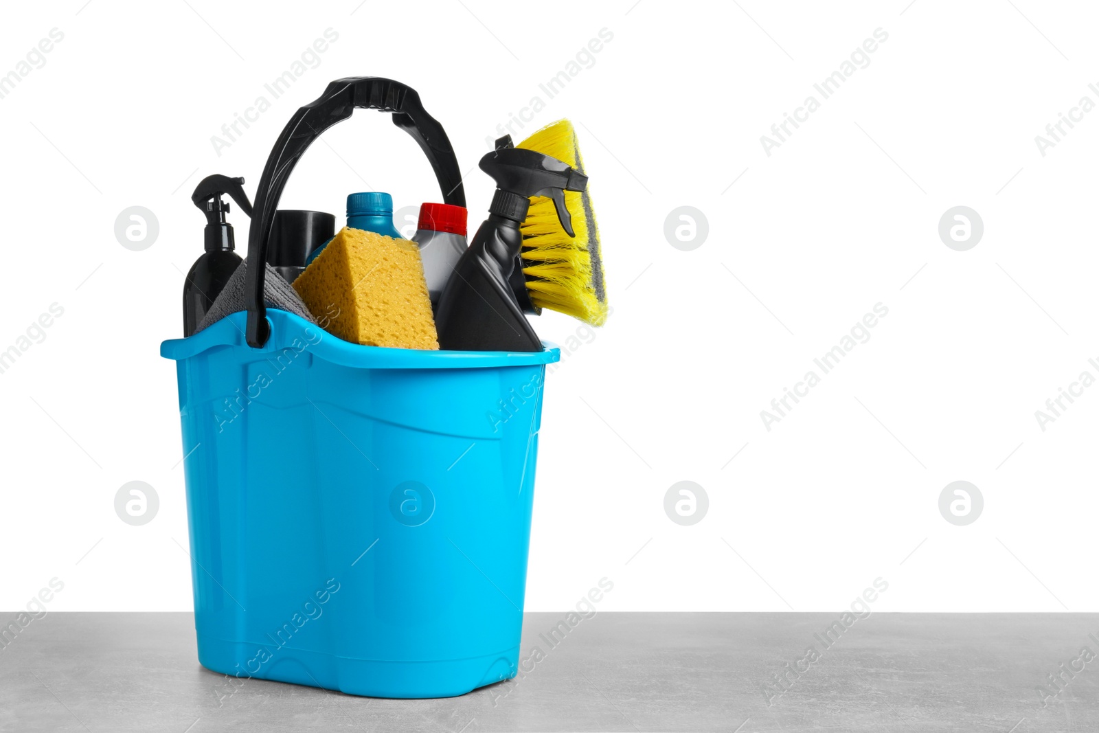 Photo of Bucket with many different car wash products on grey table against white background