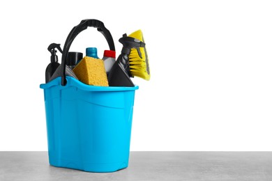 Photo of Bucket with many different car wash products on grey table against white background