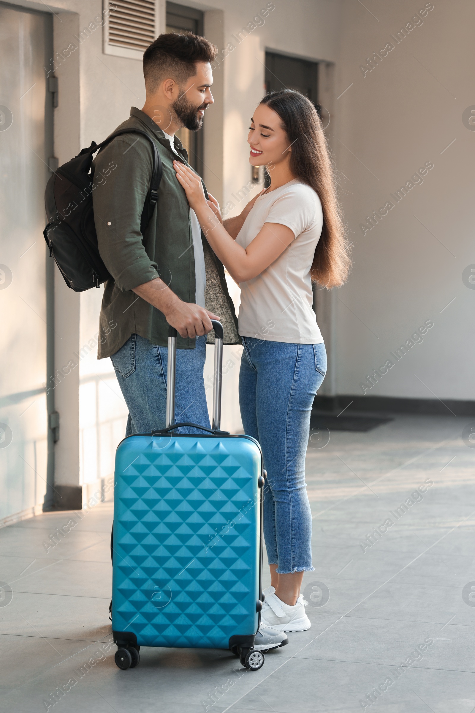 Photo of Long-distance relationship. Beautiful young couple with luggage near house entrance outdoors