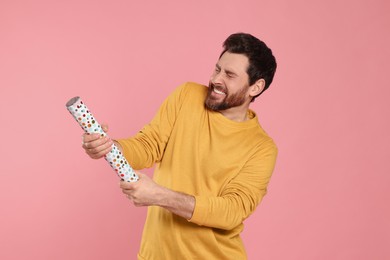 Photo of Emotional man with party popper on pink background