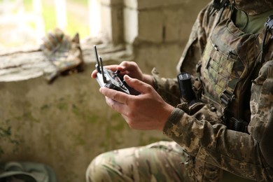 Military mission. Soldier in uniform with drone controller inside abandoned building, closeup