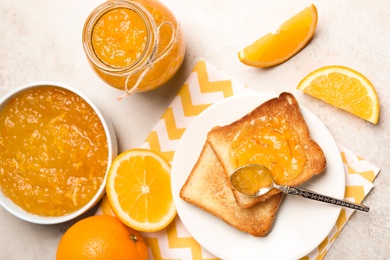 Photo of Delicious orange marmalade and toasts on light table, flat lay