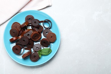 Photo of Delicious fruit leather rolls on light table, top view. Space for text