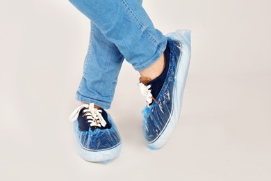 Man with blue shoe covers worn over sneakers on white background, closeup