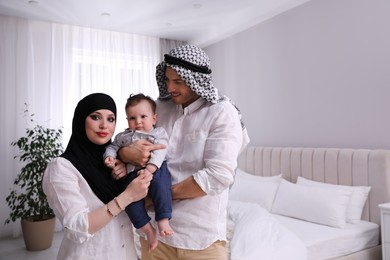 Happy Muslim family with little son in bedroom