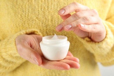 Photo of Woman holding jar of moisturizing cream, closeup. Cosmetic product for winter