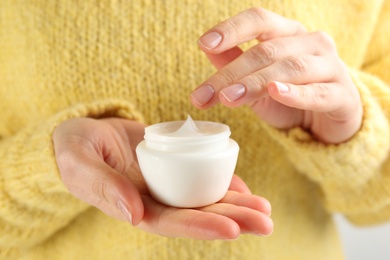 Woman holding jar of moisturizing cream, closeup. Cosmetic product for winter