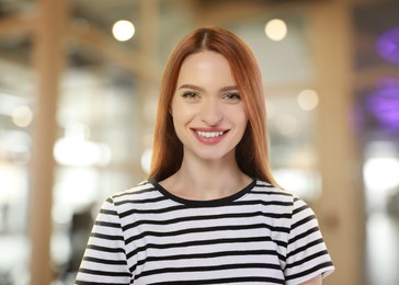 Portrait of happy woman in office. Pretty girl looking at camera and smiling on blurred background