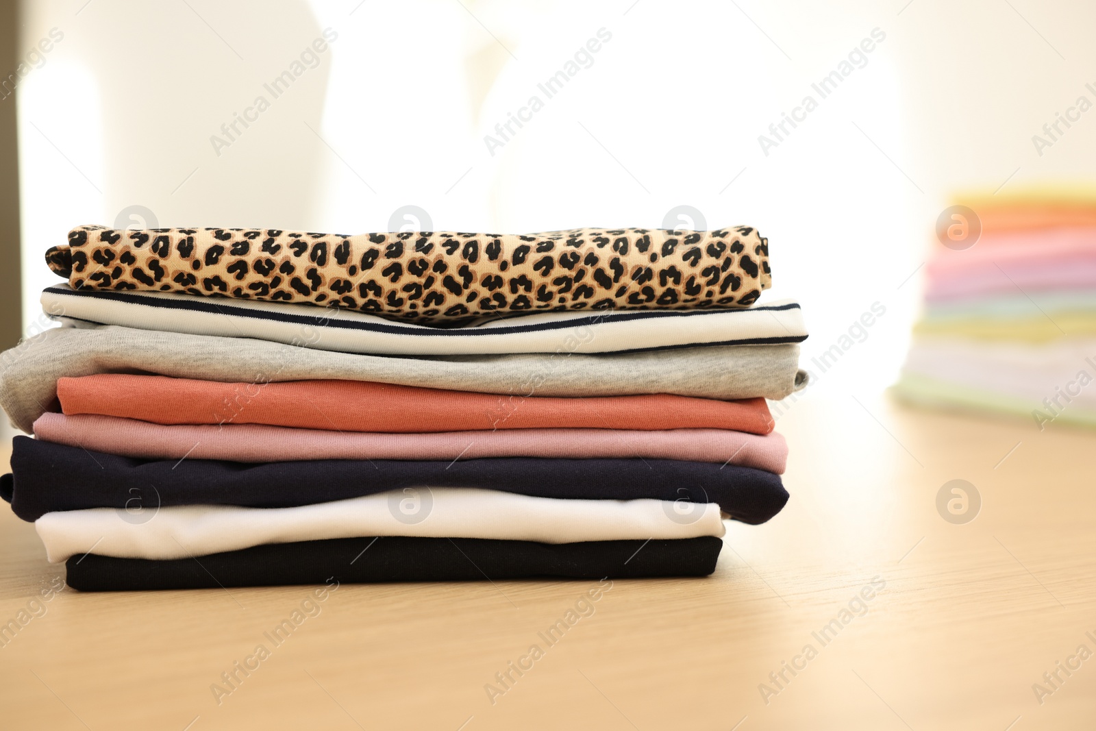 Photo of Many stacked clean clothes on wooden table