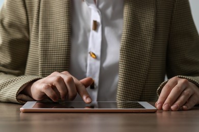 Photo of Closeup view of woman using modern tablet at wooden table