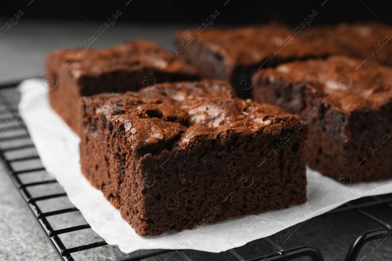 Photo of Cooling rack with fresh brownies on grey table, closeup. Delicious chocolate pie