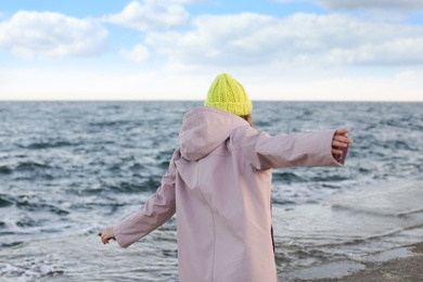 Young woman in warm clothes time near sea