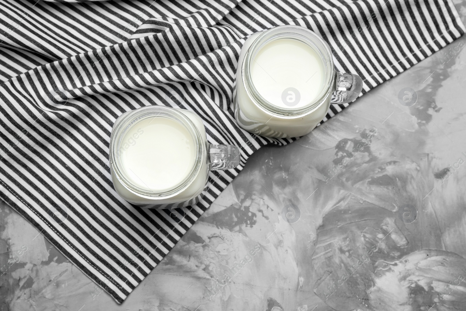 Photo of Mason jars with milk on grey background