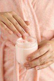Photo of Woman holding jar of hand cream, closeup