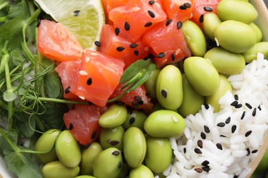 Photo of Delicious poke bowl with lime, fish and edamame beans, top view