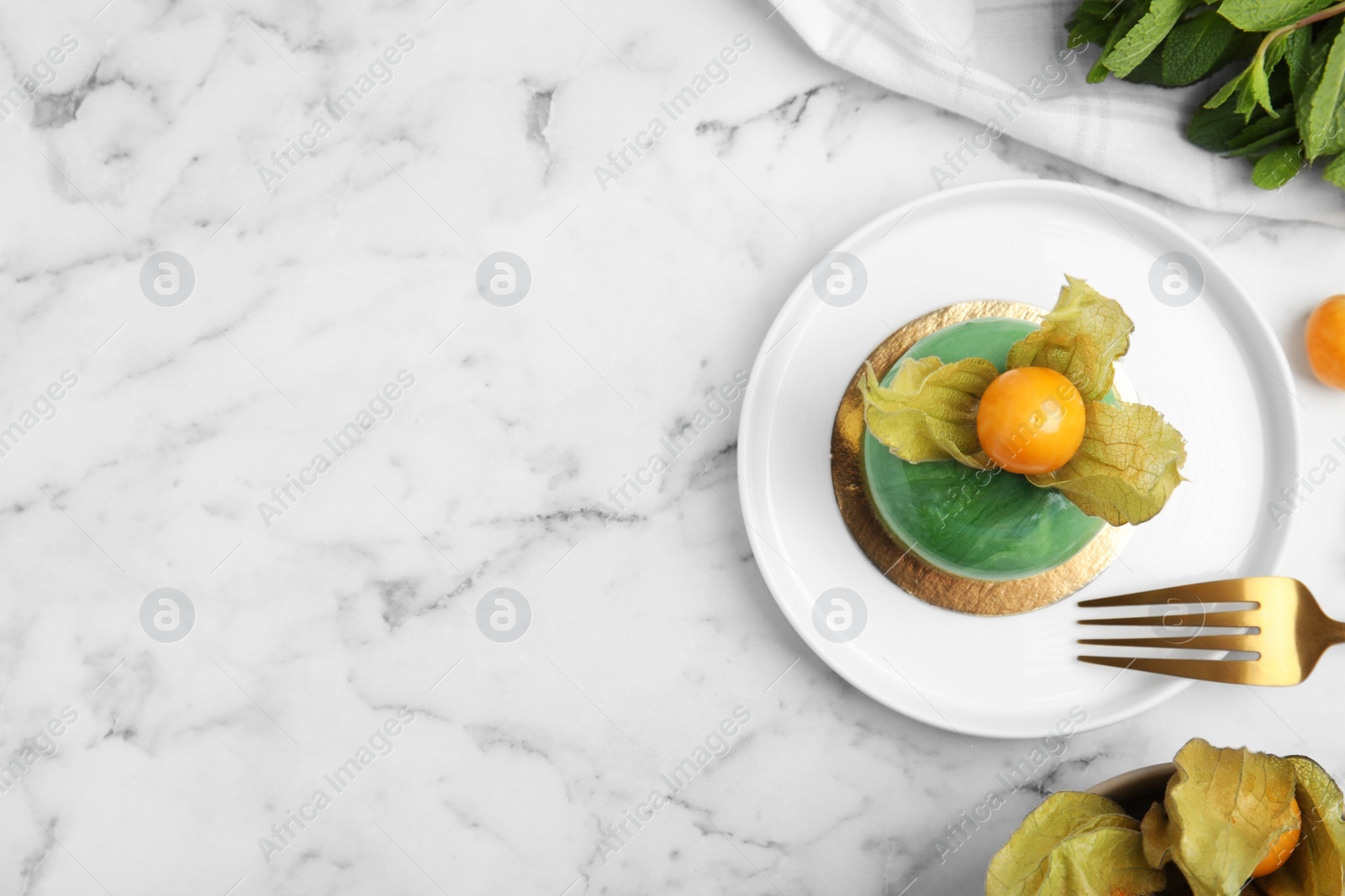 Photo of Delicious mousse cake decorated with physalis fruit on white marble table, flat lay. Space for text