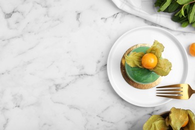 Photo of Delicious mousse cake decorated with physalis fruit on white marble table, flat lay. Space for text