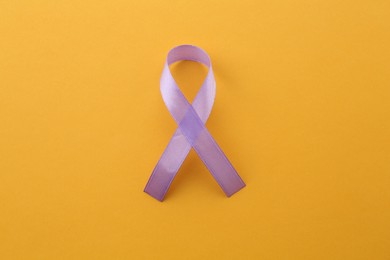 Violet awareness ribbon on orange background, top view