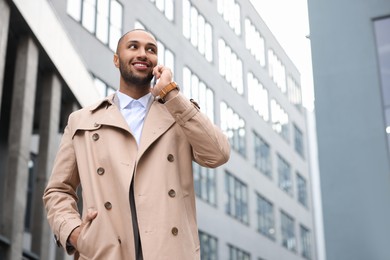 Happy man talking on smartphone outdoors, space for text. Lawyer, businessman, accountant or manager