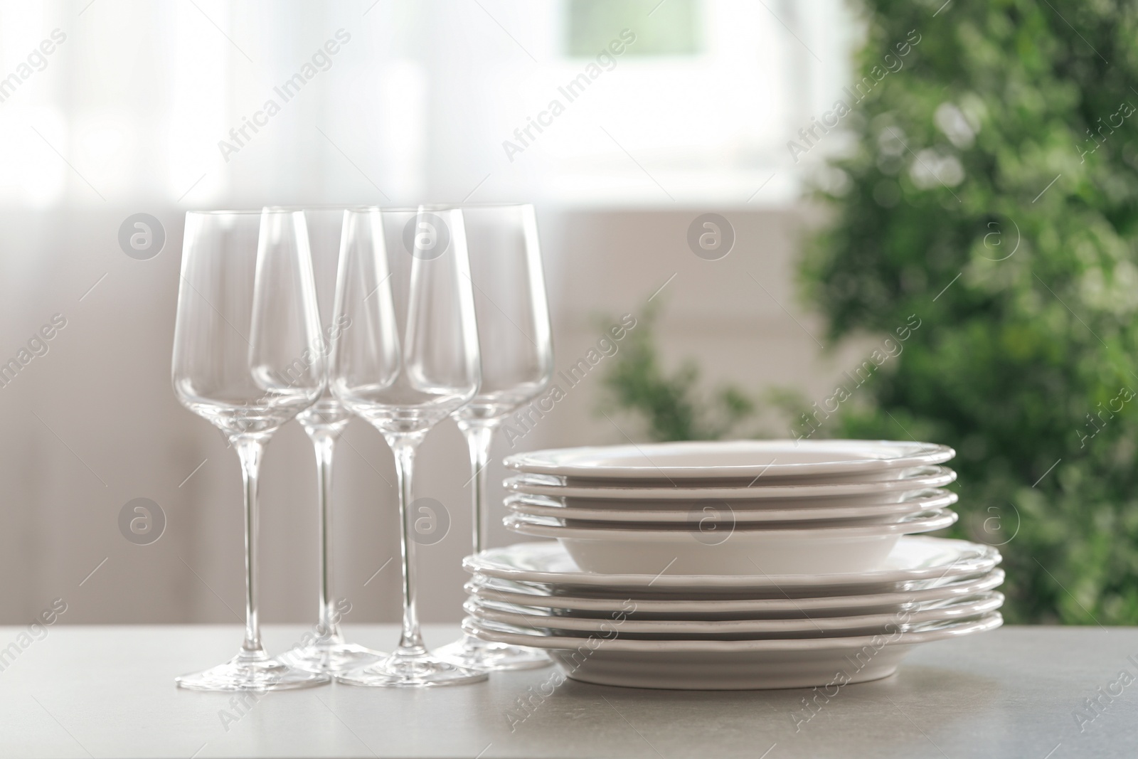 Photo of Set of clean dishes and wineglasses on table indoors