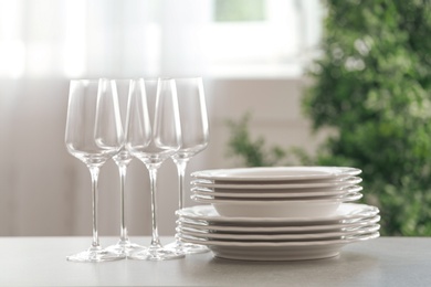 Photo of Set of clean dishes and wineglasses on table indoors