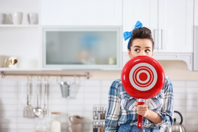 Photo of Funny young housewife with frying pan in kitchen